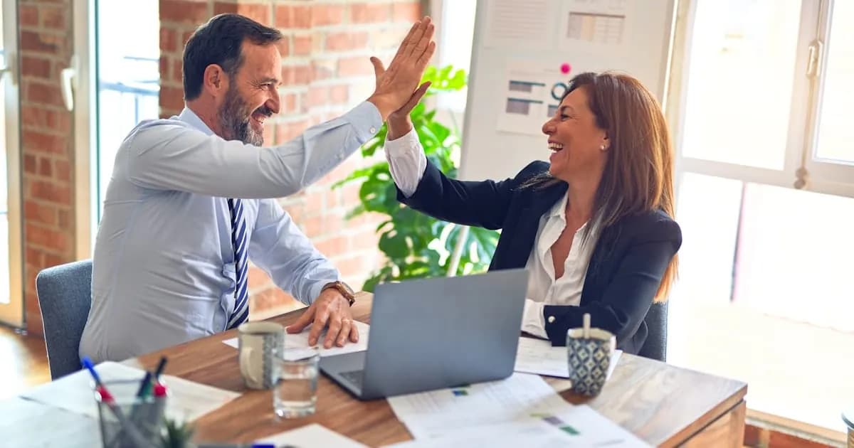 Two support teammates high-fiving at their desk